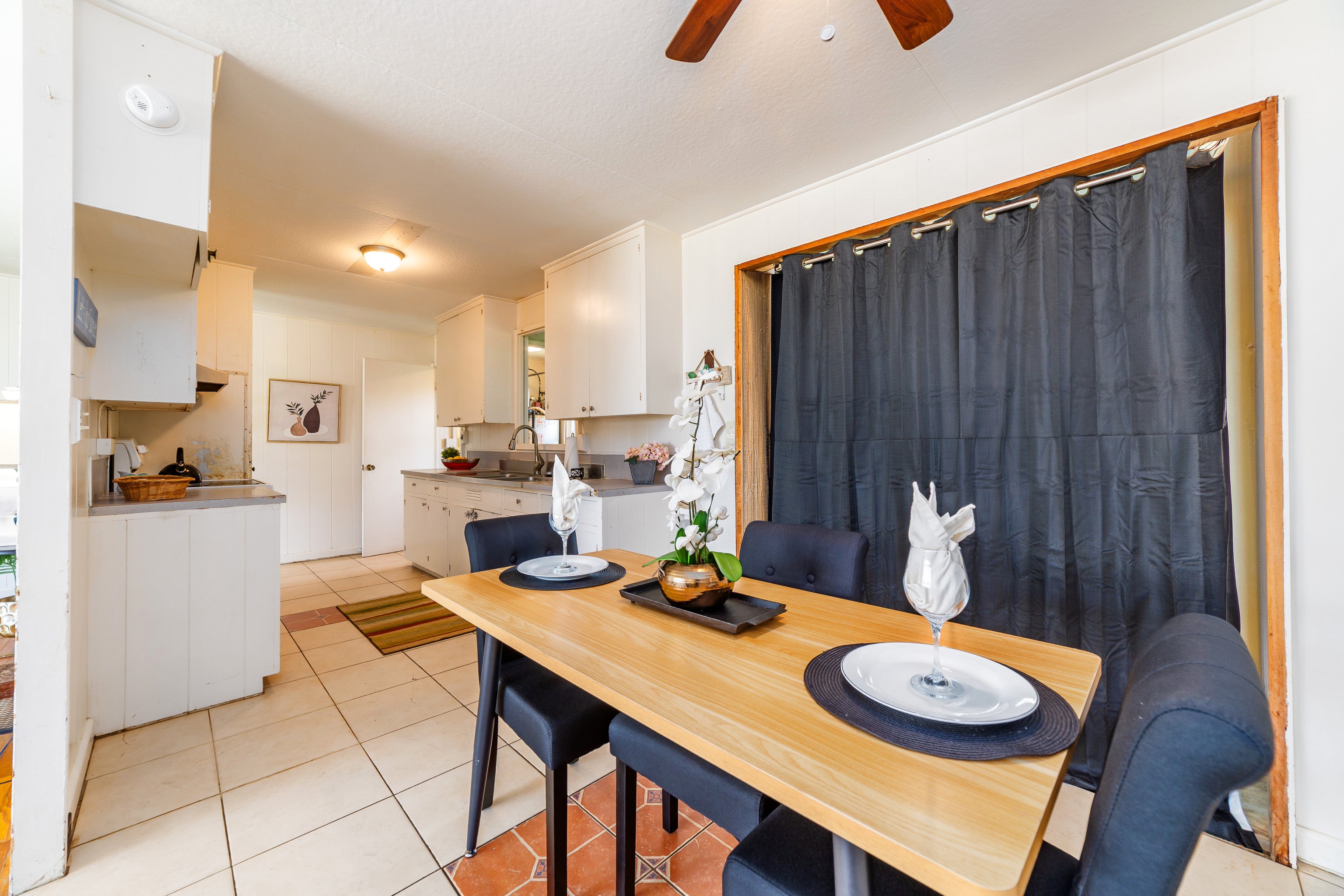 Kitchen and dining area with a wood table, dark chairs, and white orchid