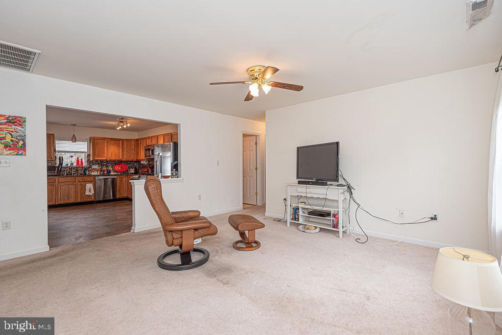 Living room with a leather recliner and TV, opening onto a wood-cabinet kitchen.