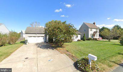 Home with a wide driveway, front garage, and large tree partly obscuring the facade.