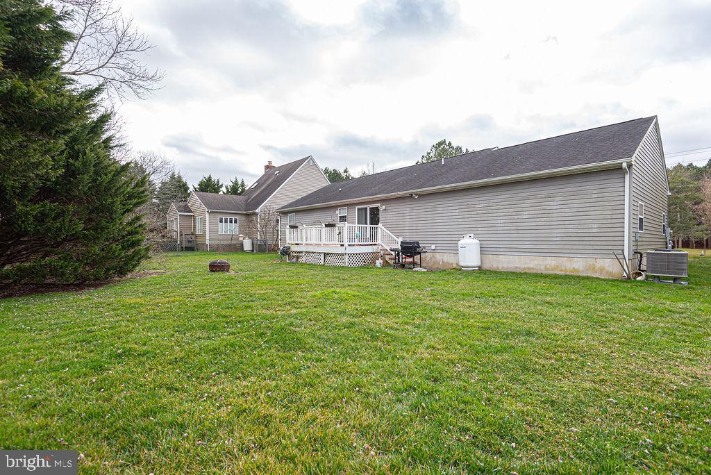 Rear of a gray-sided home with a raised deck and broad green lawn.