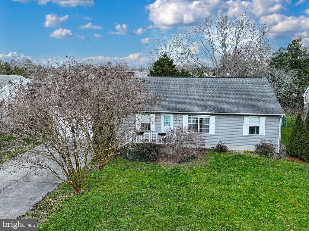 Gray single-story home with a covered front porch, lawn, and driveway.