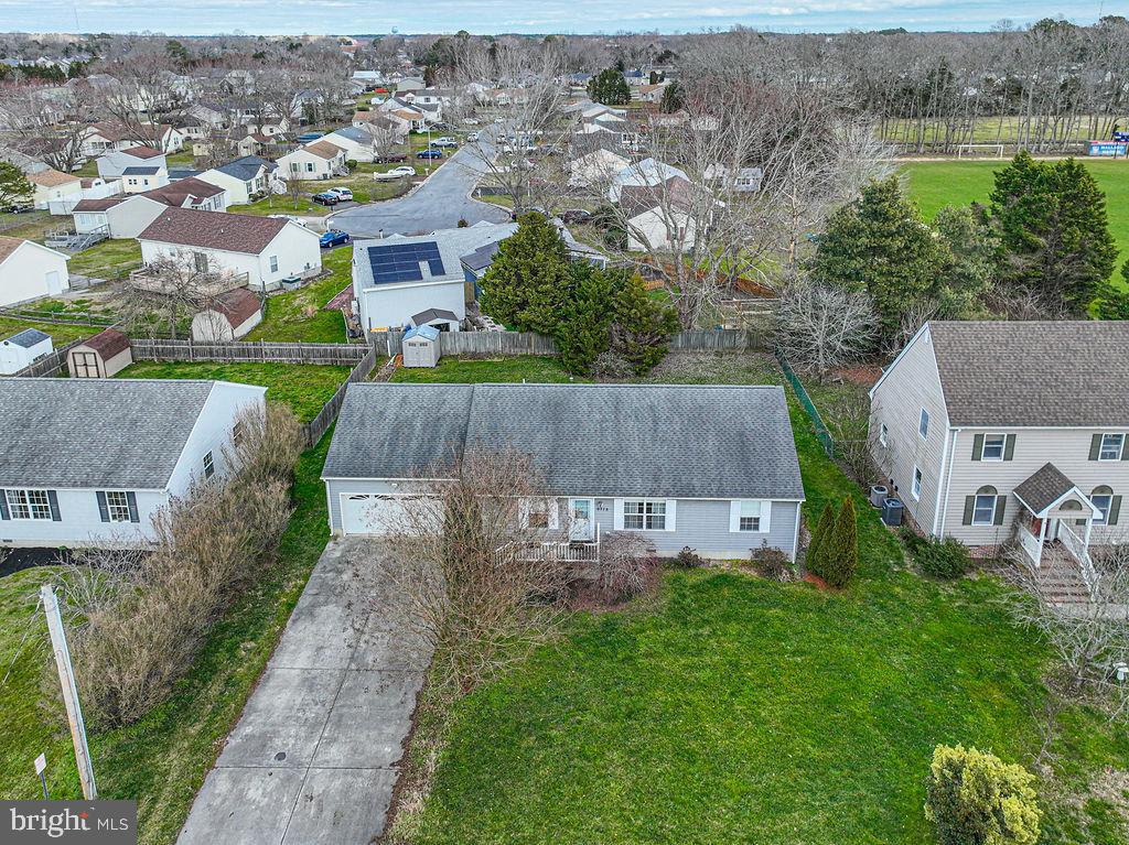 Single-story gray home with a broad lawn and concrete driveway, seen from above.
