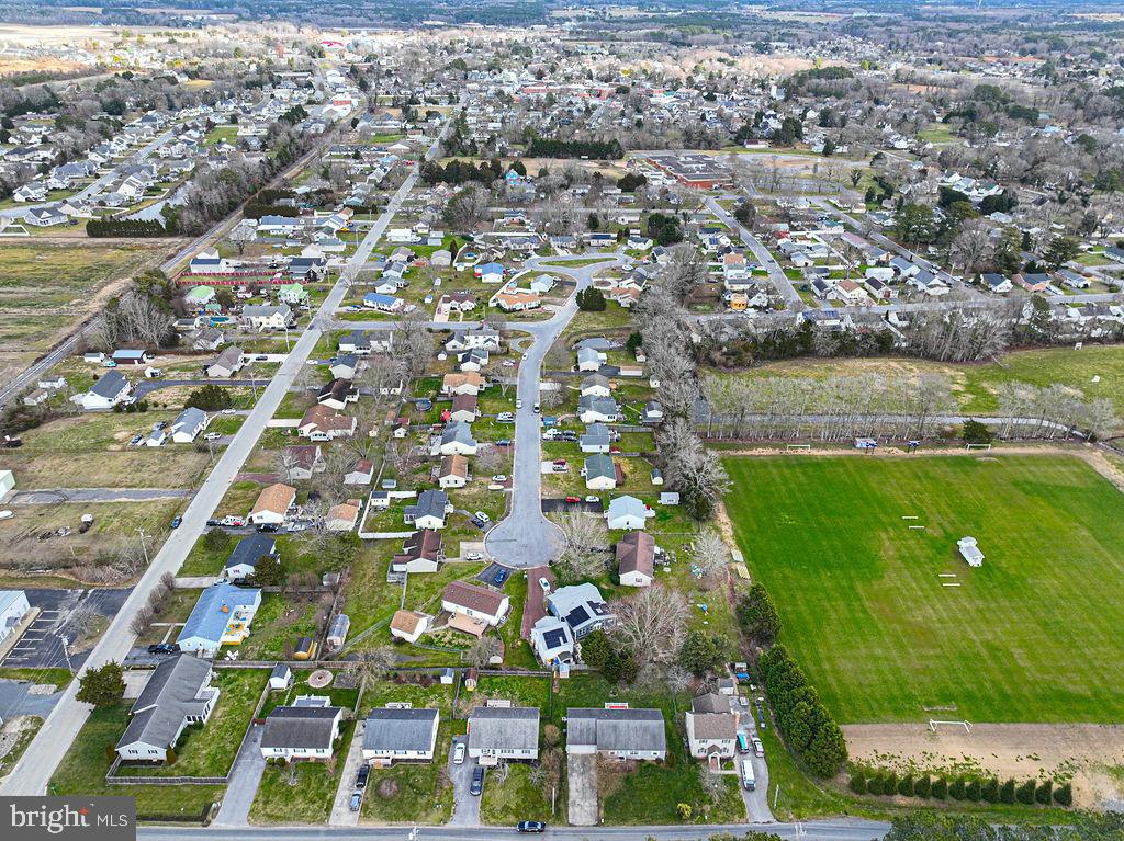 Aerial view of homes along neighborhood streets beside a large green sports field.