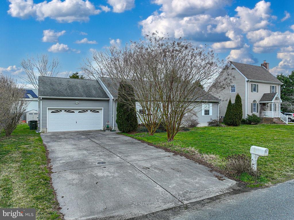 Light-sided two-story home with a broad driveway, garage wing, and leafless trees across the front lawn.