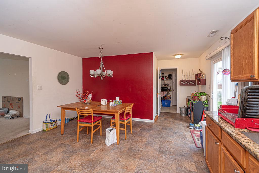 Dining area with a wooden table, red accent wall, and kitchen cabinetry along the right side.