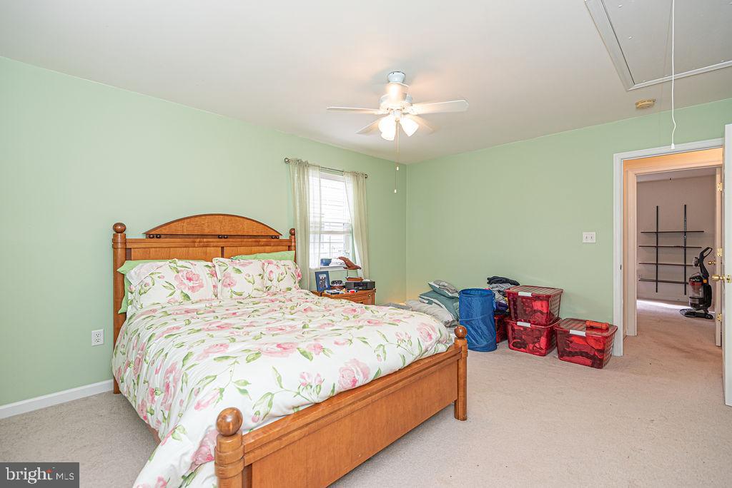 Bedroom with a wooden bed, floral bedding, pale green walls, and storage bins beside the doorway.