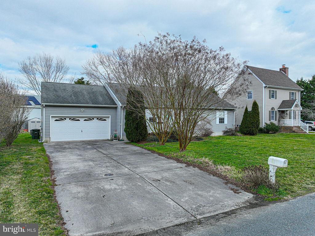 Gray two-story house with a white porch, attached garage, and wide concrete driveway.