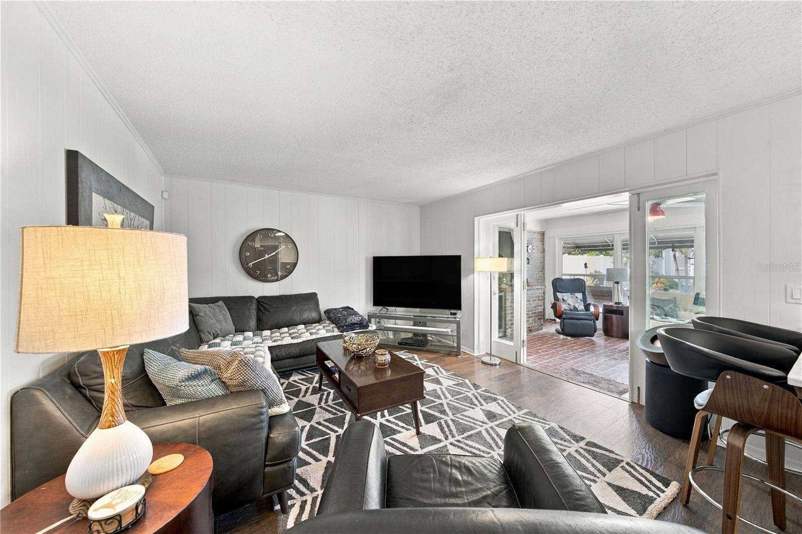 Living room with leather sofas, a geometric rug, and sliding doors to a brick-floored sunroom.
