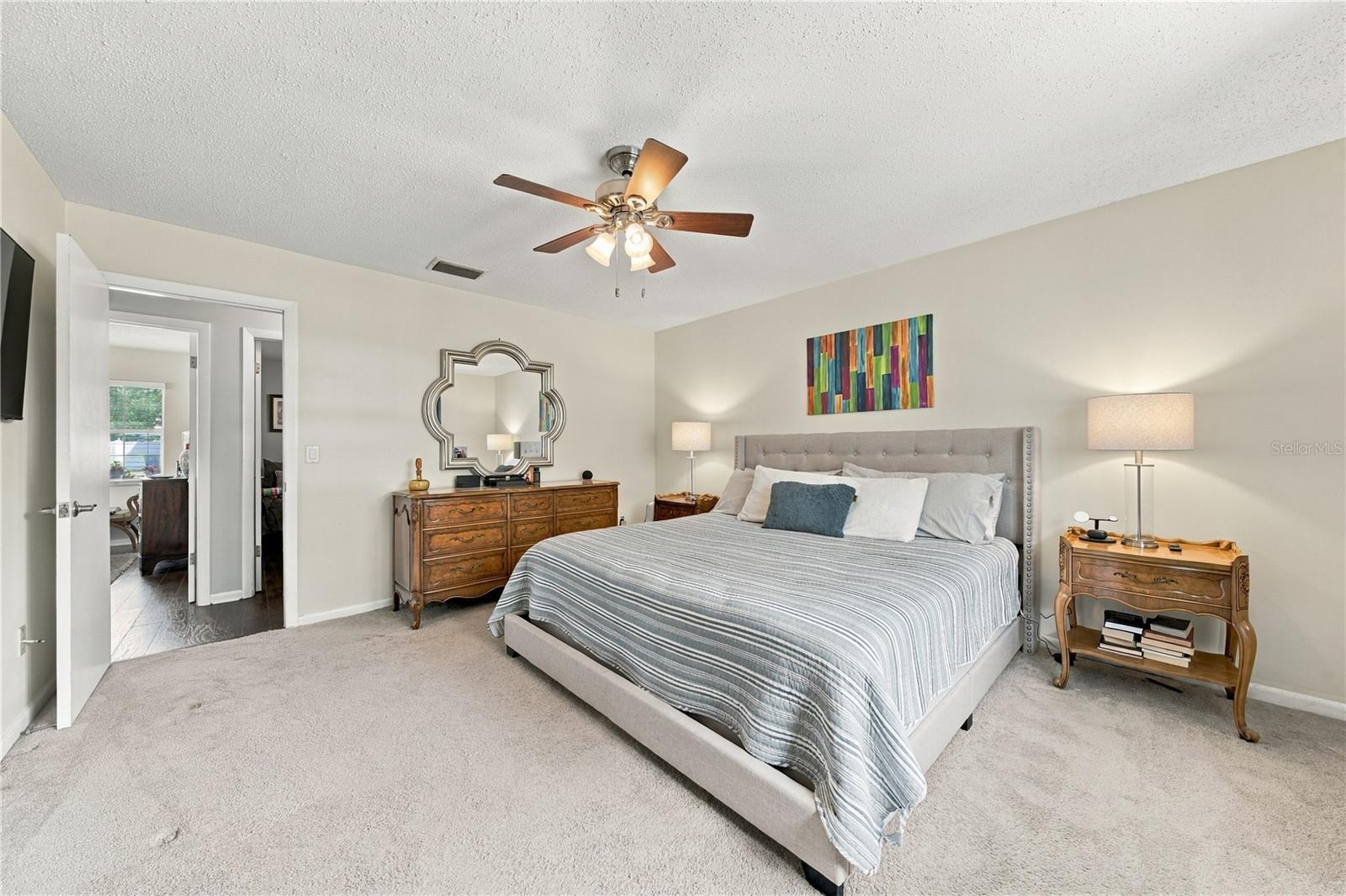 Primary bedroom with a large striped bed, tufted headboard, and matching wood bedside tables.
