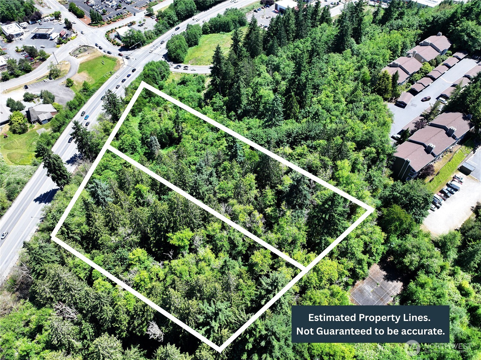 Aerial view of a wooded parcel outlined with estimated property lines beside a major road.