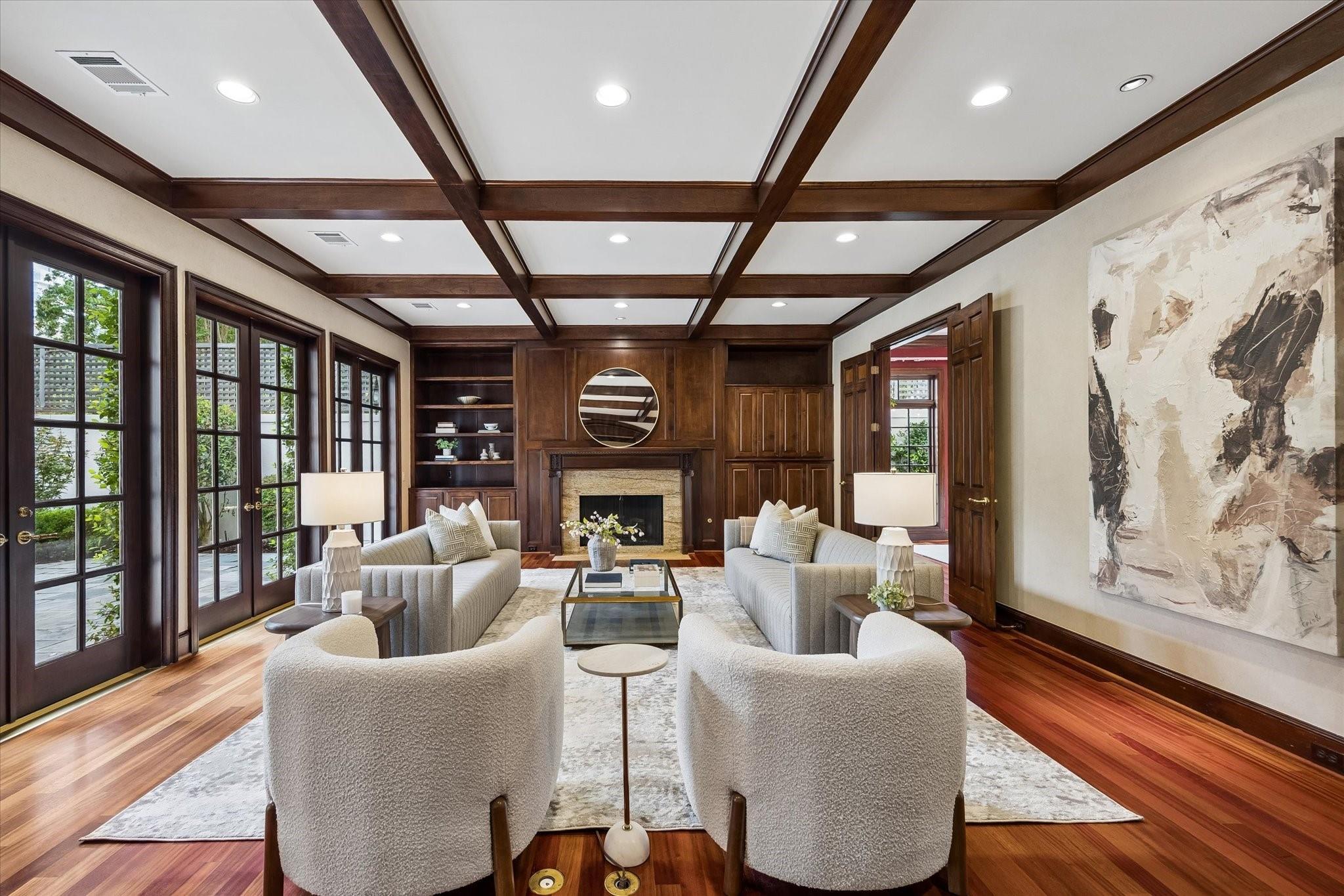 Living room with a beamed ceiling, built-in cabinetry, fireplace and French doors.
