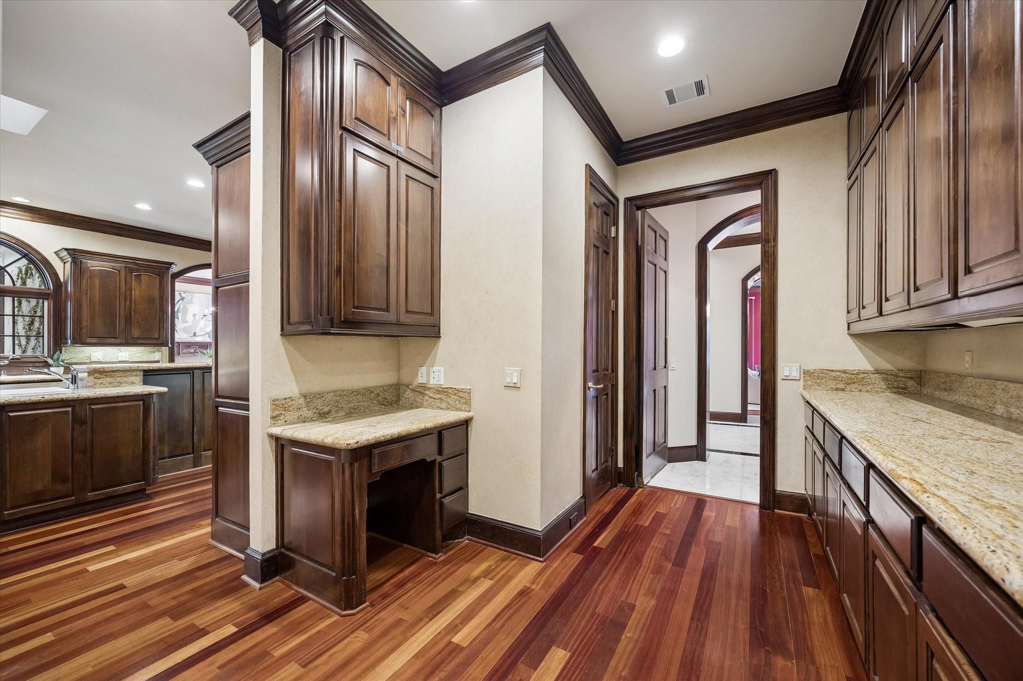 Kitchen with dark wood cabinetry, granite counters, and reddish hardwood floors.
