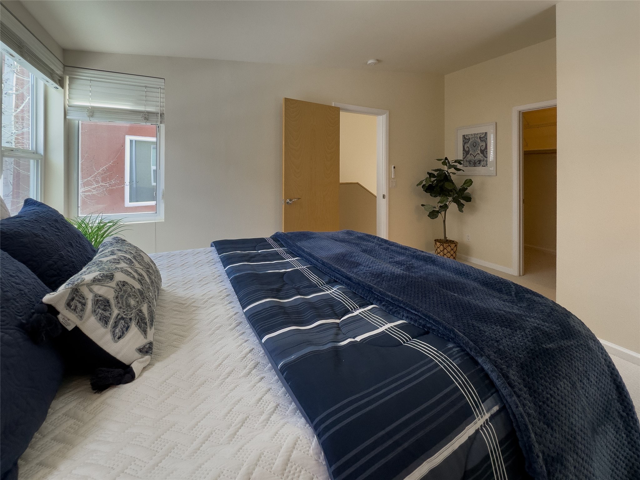 Furnished bedroom with navy bedding, two windows, and an open doorway.
