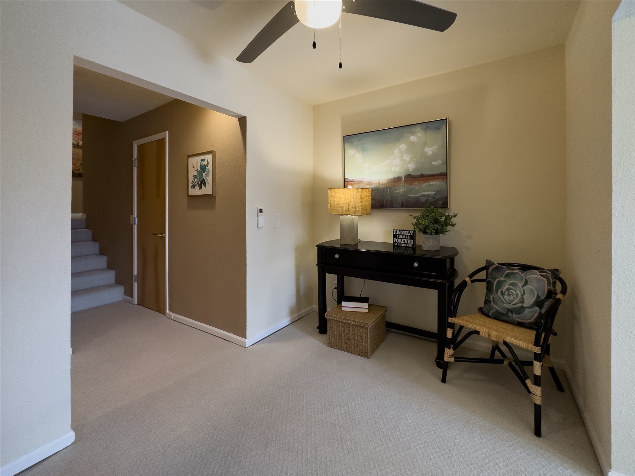 Furnished entryway with a carpeted staircase, console table, and woven chair.