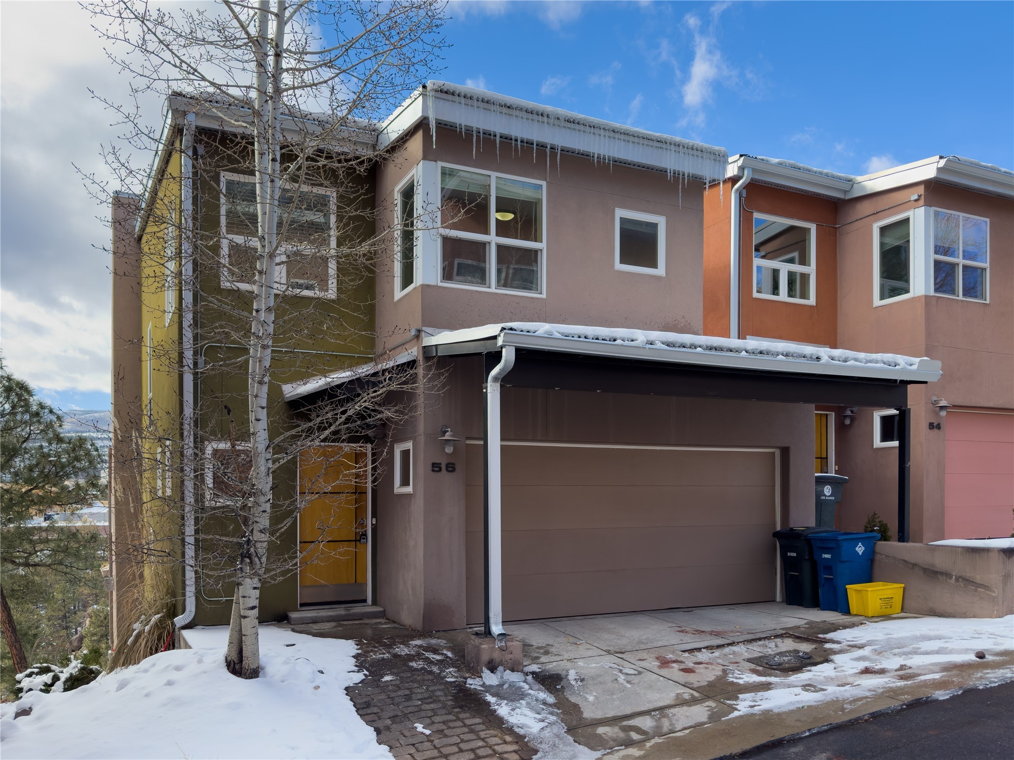 Two-story home with a covered garage, snow-covered ground, and icicles hanging from the roof.