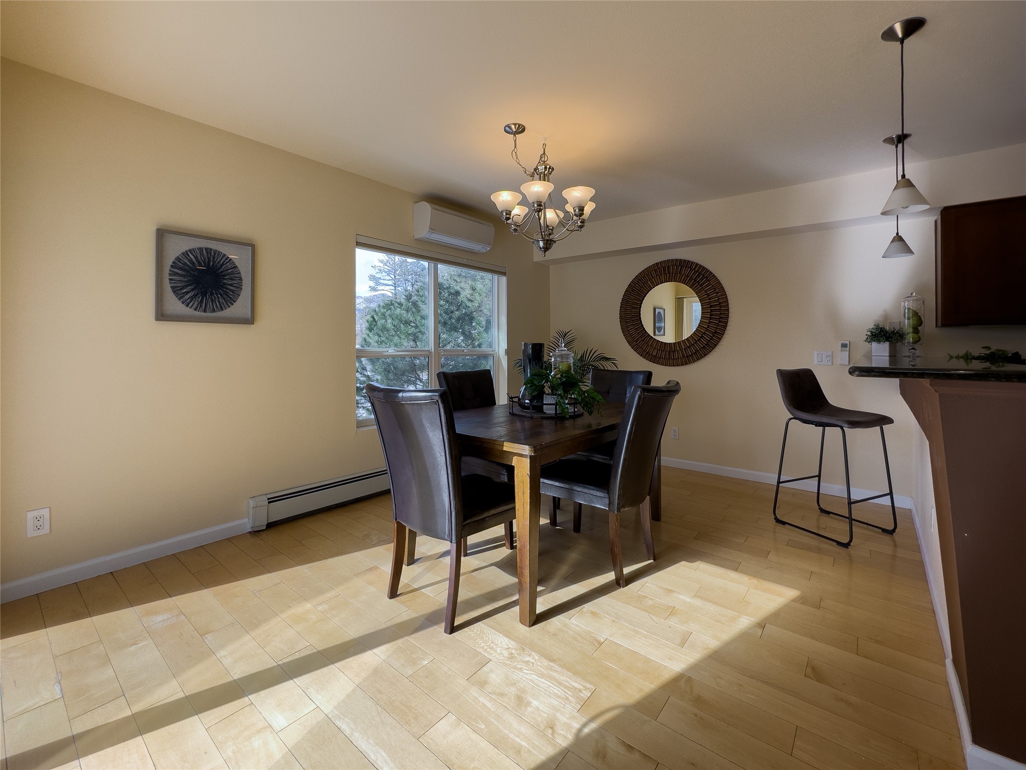 Dining area with a dark wood table, leather chairs, tile floor, and window overlooking trees.