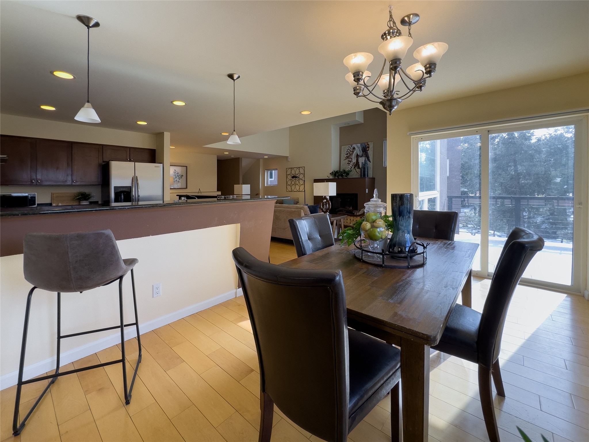 Dining area with a dark wood table beside the kitchen and sliding doors overlooking a snowy deck.
