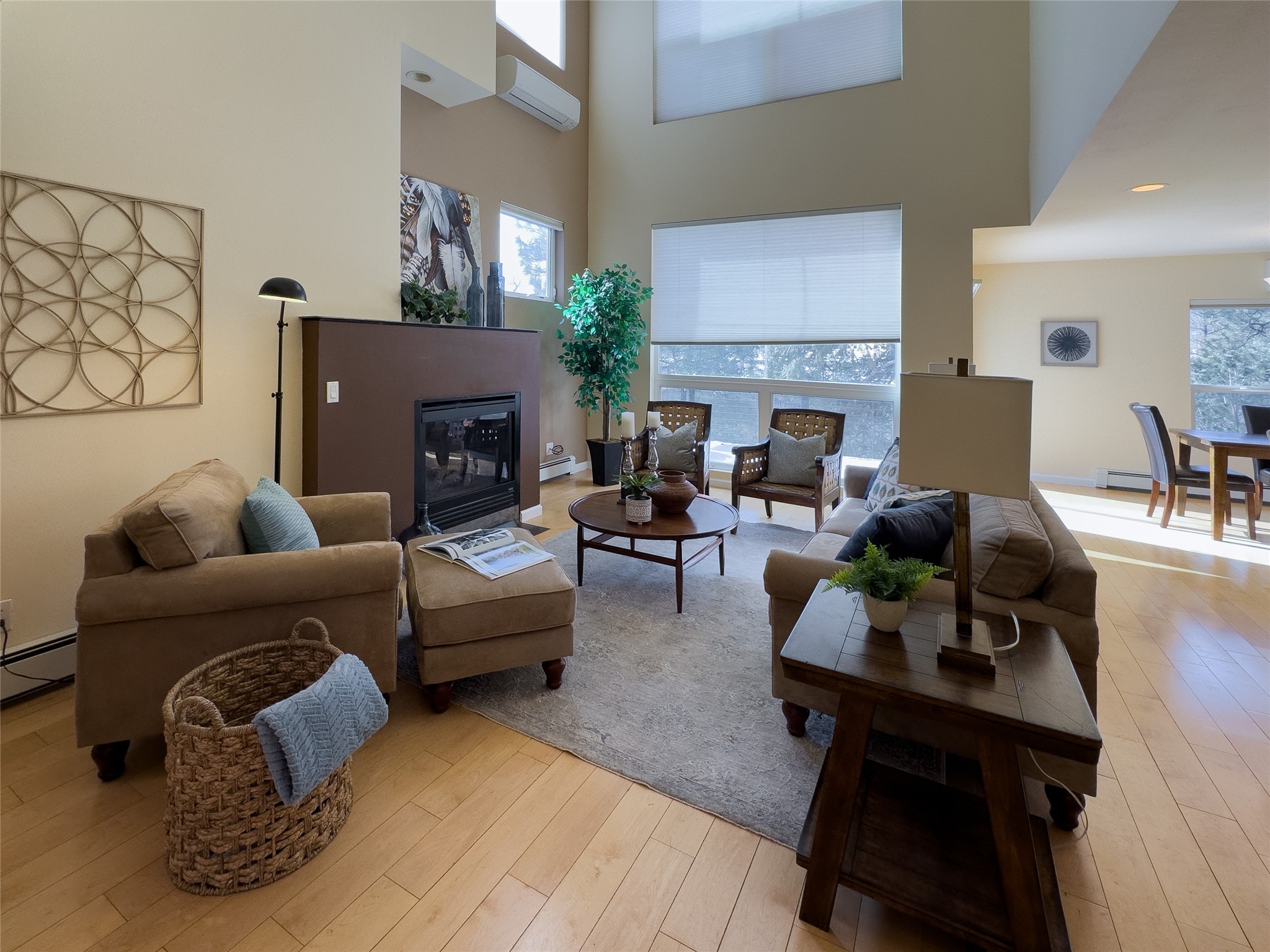 Living room with a fireplace, tall windows, and seating arranged around a round coffee table.