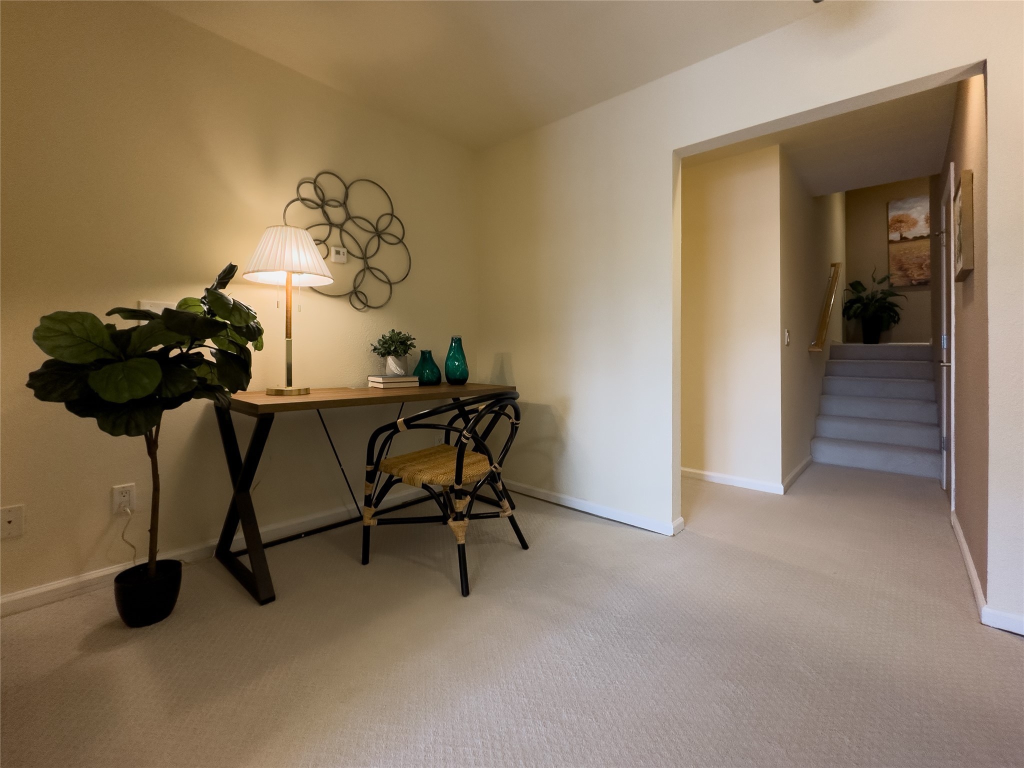 Furnished entry hall with a desk and chair beside a carpeted staircase.