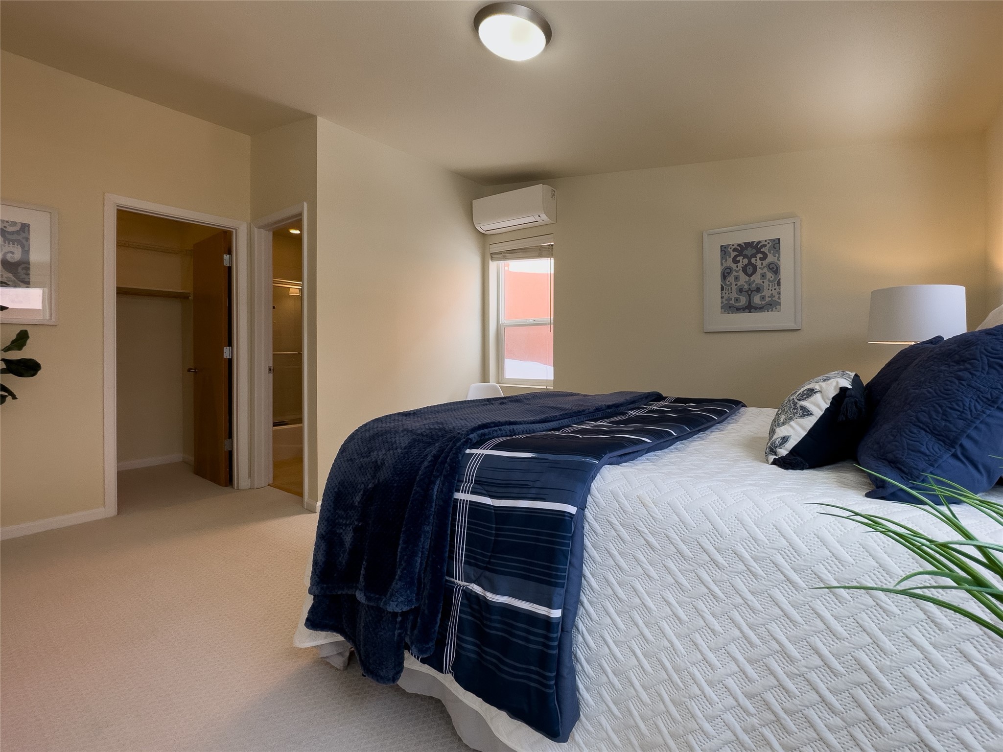 Furnished bedroom with a large bed, navy bedding, beige carpet, and an open closet.