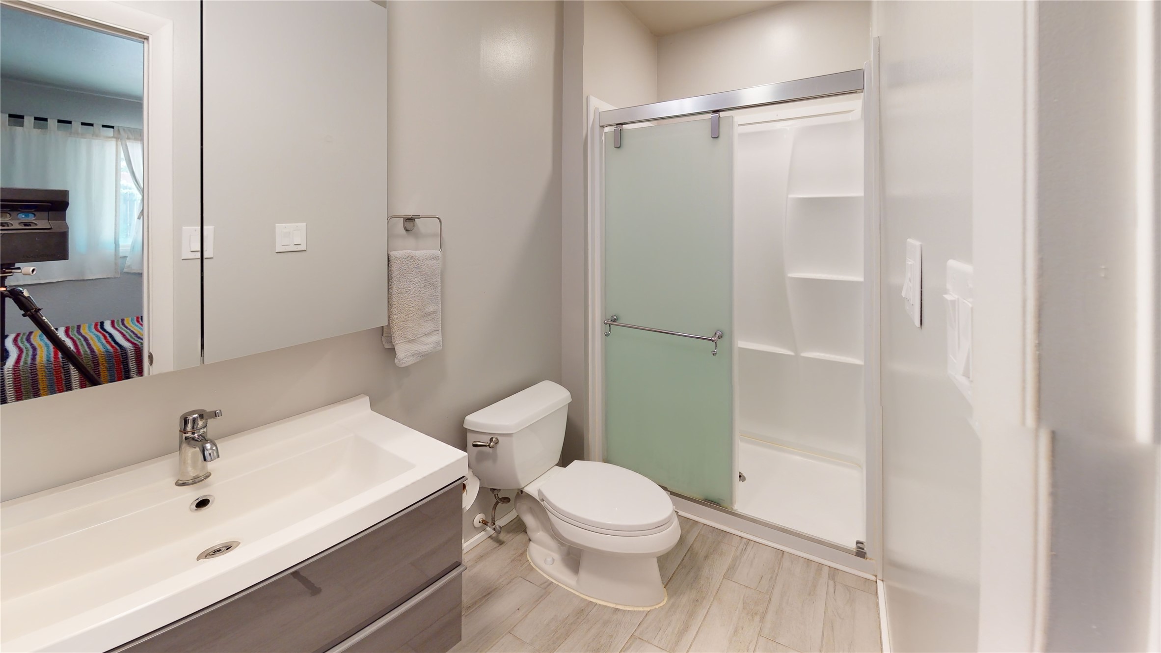 Bathroom with a wide vanity, toilet, and shower behind a frosted-glass sliding door.