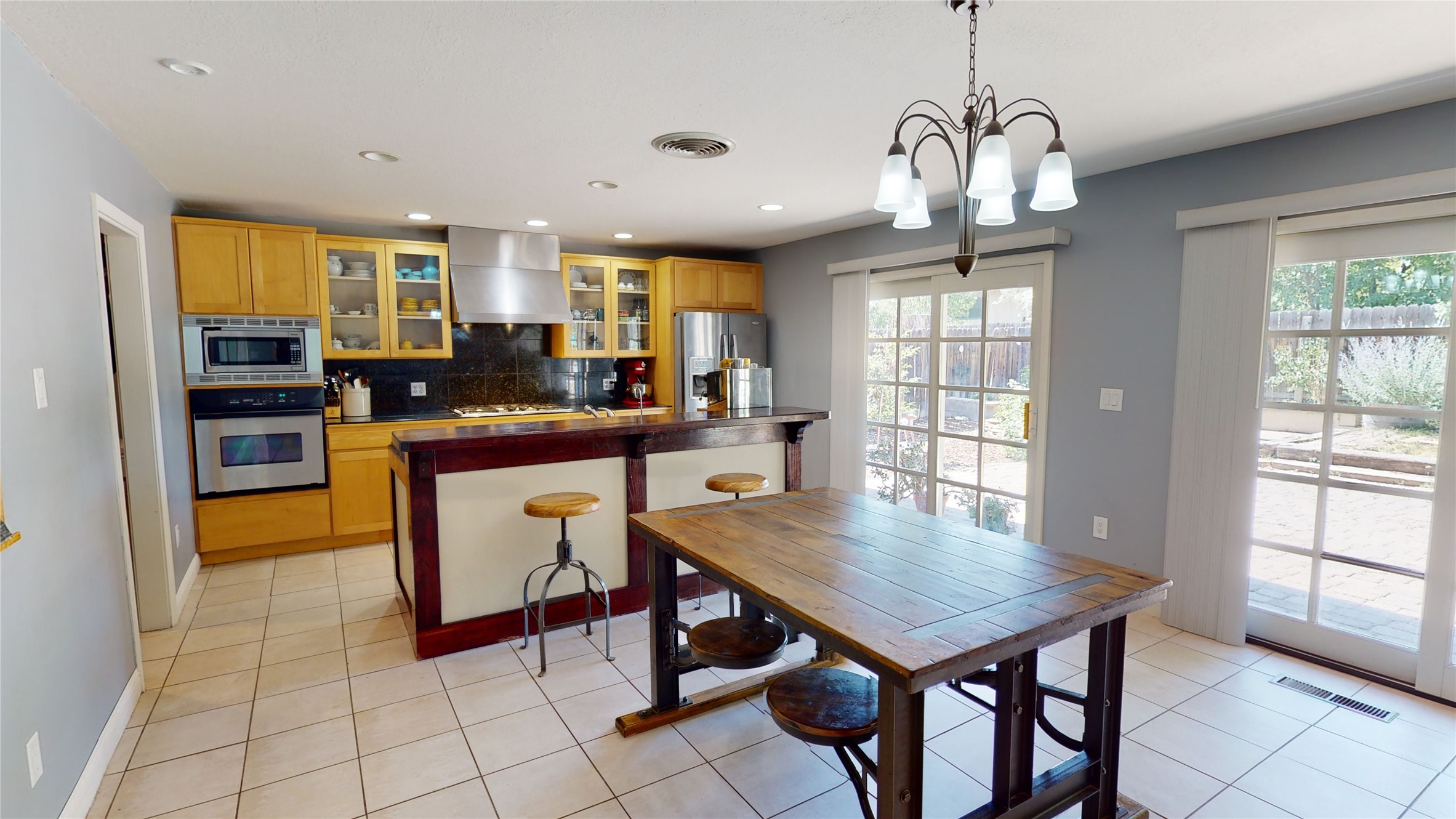 Kitchen and dining area with wood cabinetry, a breakfast bar, and a rustic table by large windows.