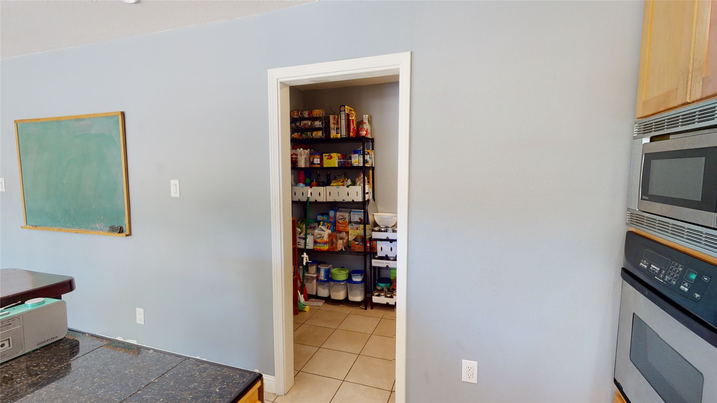 Kitchen pantry stocked with food on open shelves, viewed beside a built-in double oven.