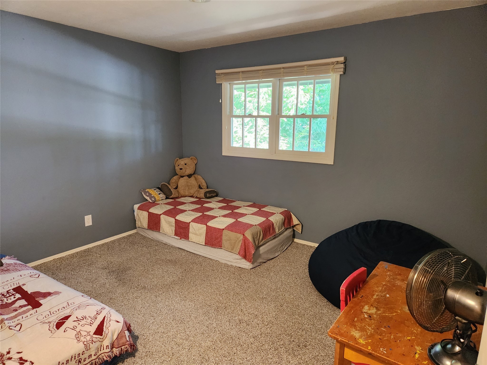 Bedroom with gray walls, two twin beds, a teddy bear, and a window with blinds.