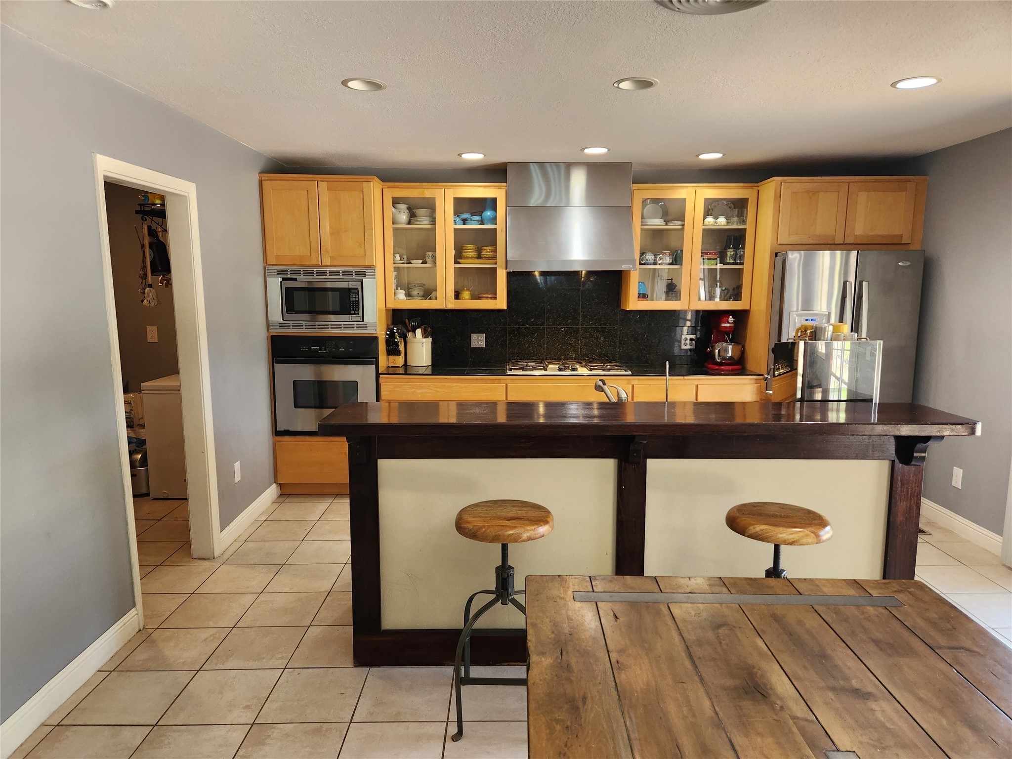 Kitchen with wood cabinets, stainless appliances, and a large island with two stools.