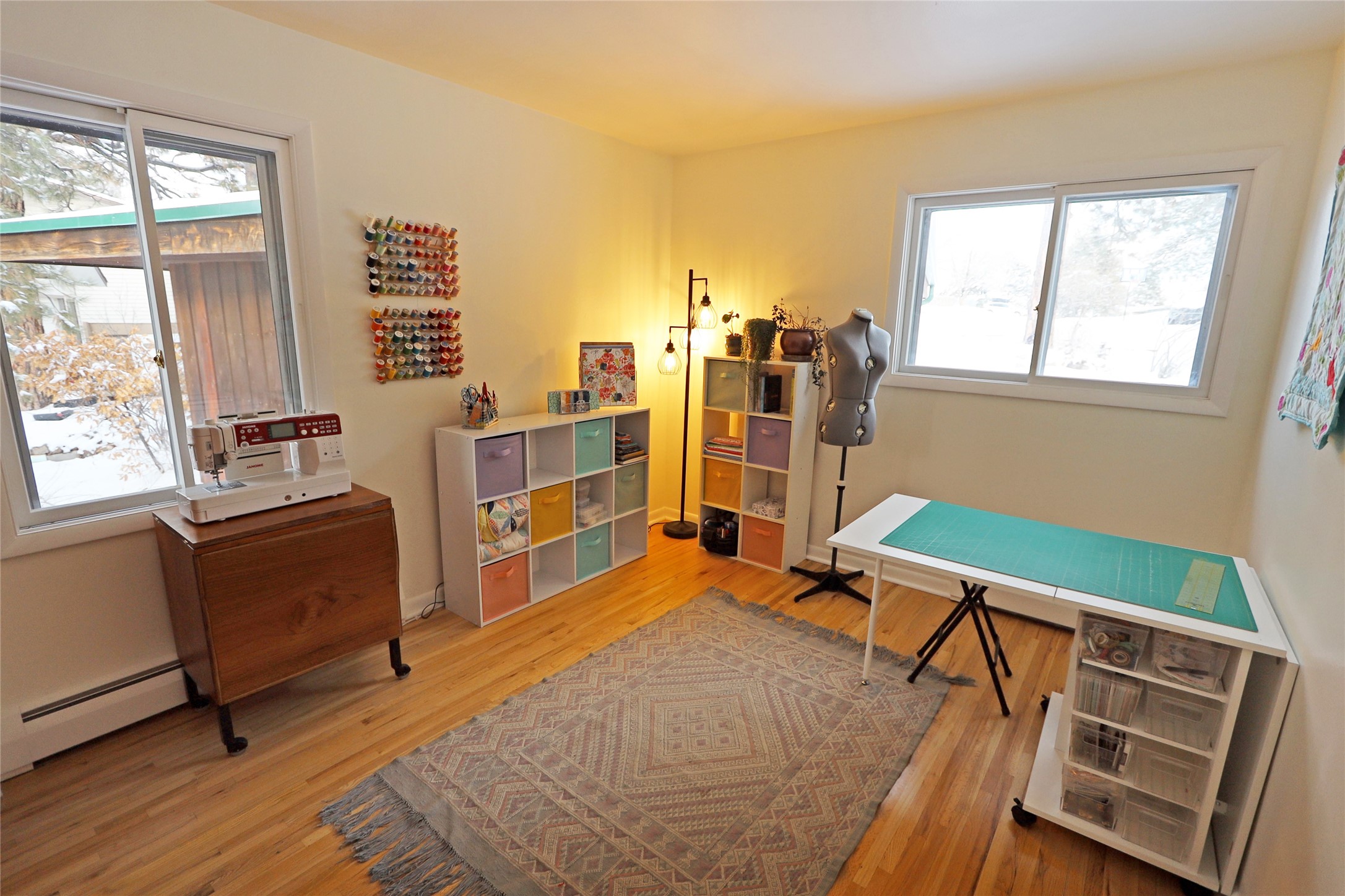 Sewing room with colorful thread racks, a dress form, and a turquoise cutting mat.