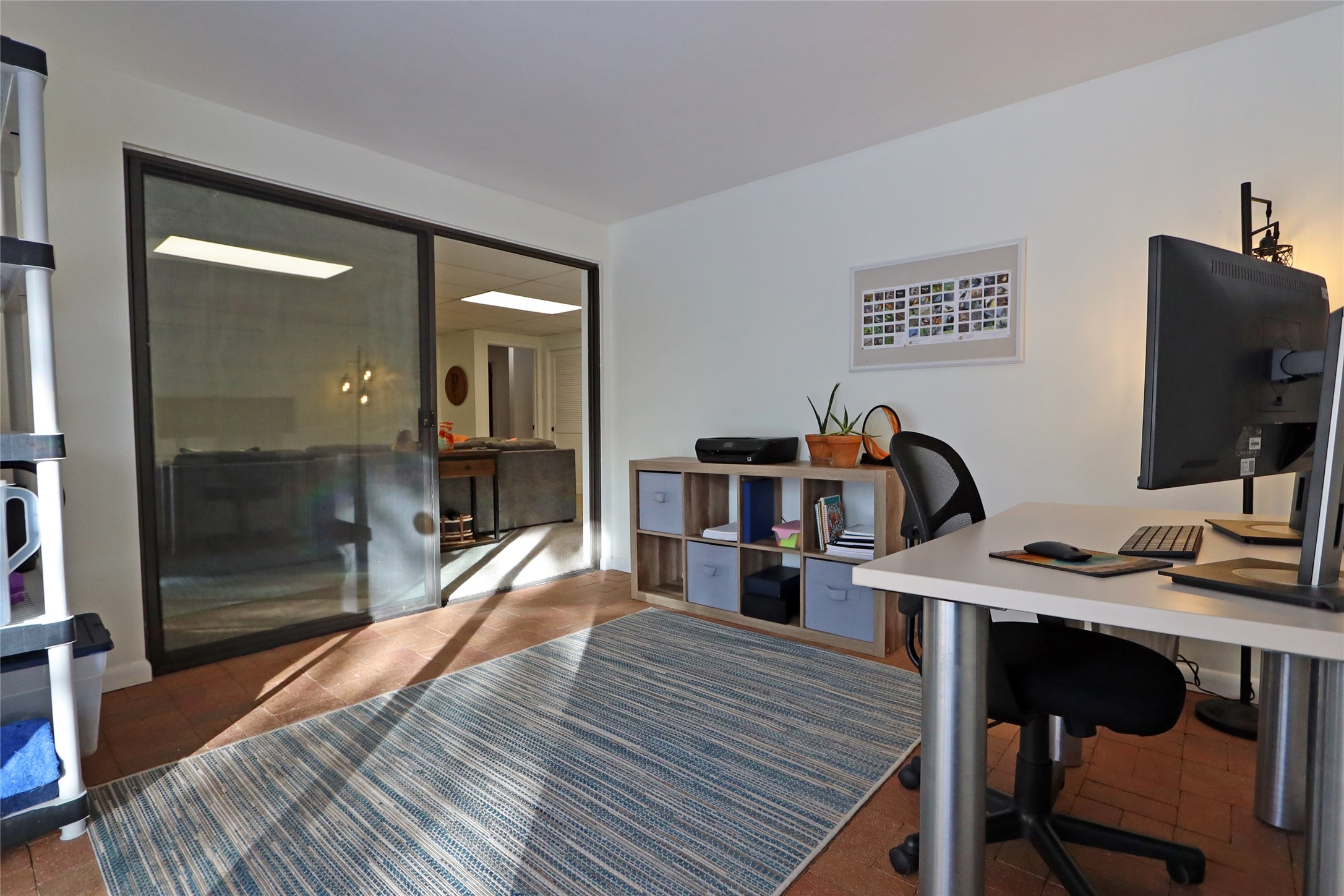 Home office with a desk and computer, sliding glass doors, and a blue patterned rug.
