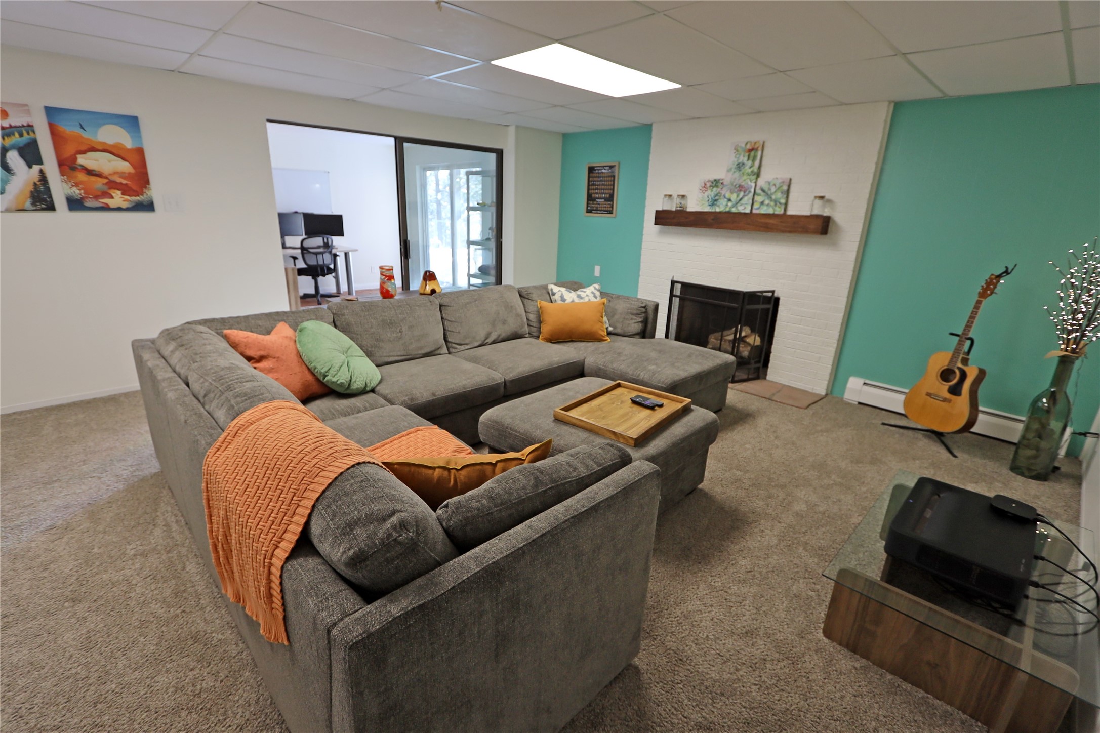 Living room with a gray sectional, white brick fireplace, and turquoise accent wall.
