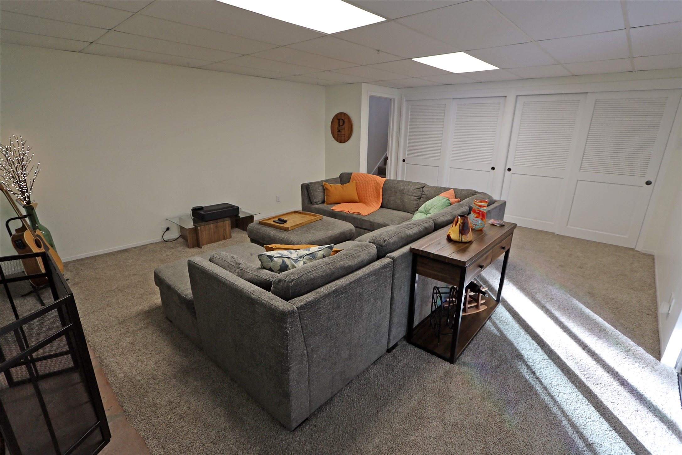 Living room with a large gray sectional, colorful pillows, and white louvered closet doors.