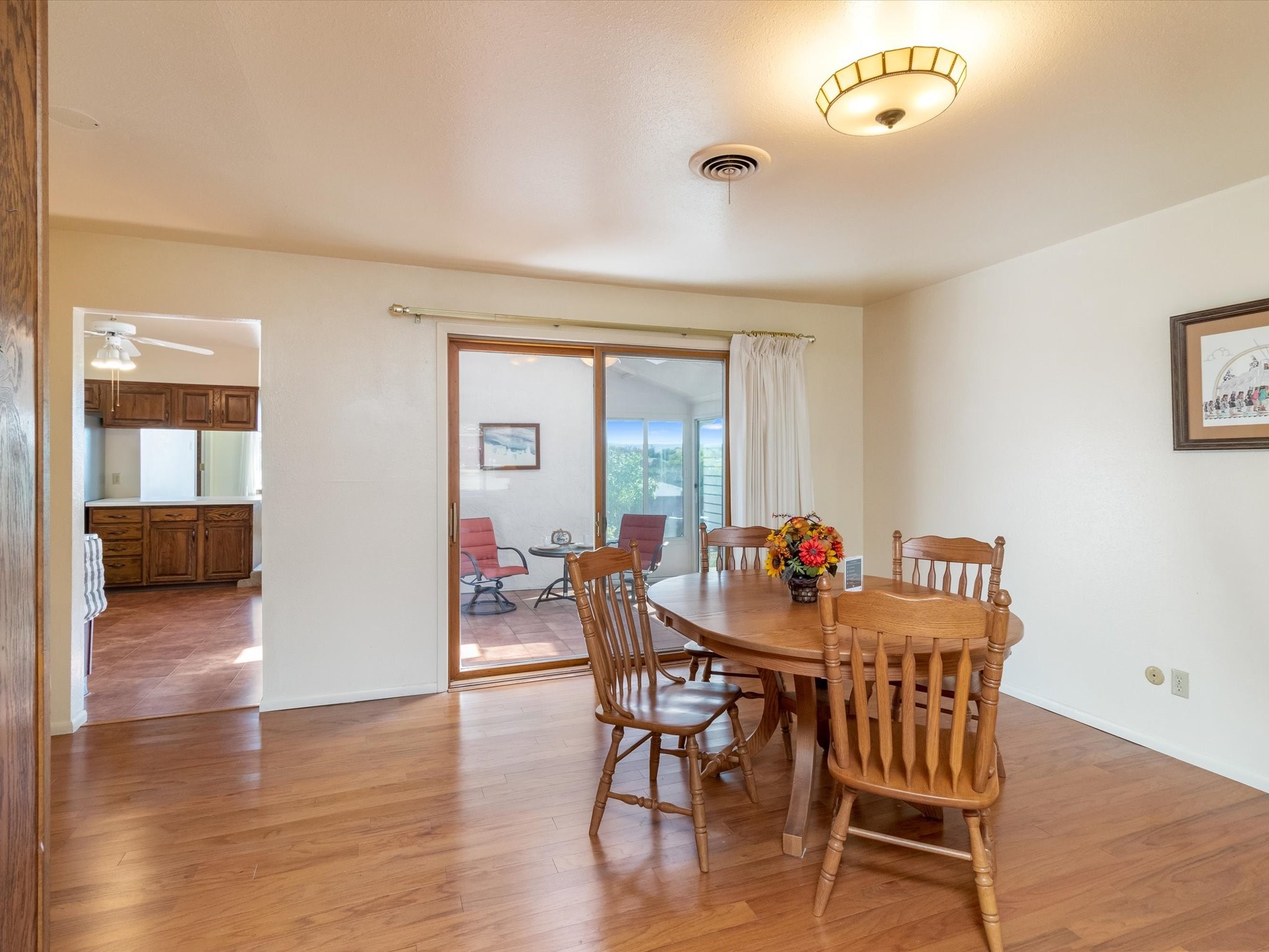 Dining room with a wooden table beside a sliding glass door opening onto a patio.