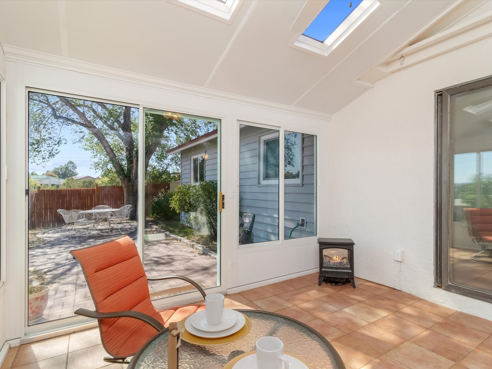 Furnished sunroom with skylights, sliding glass doors, and a view of the paved patio.