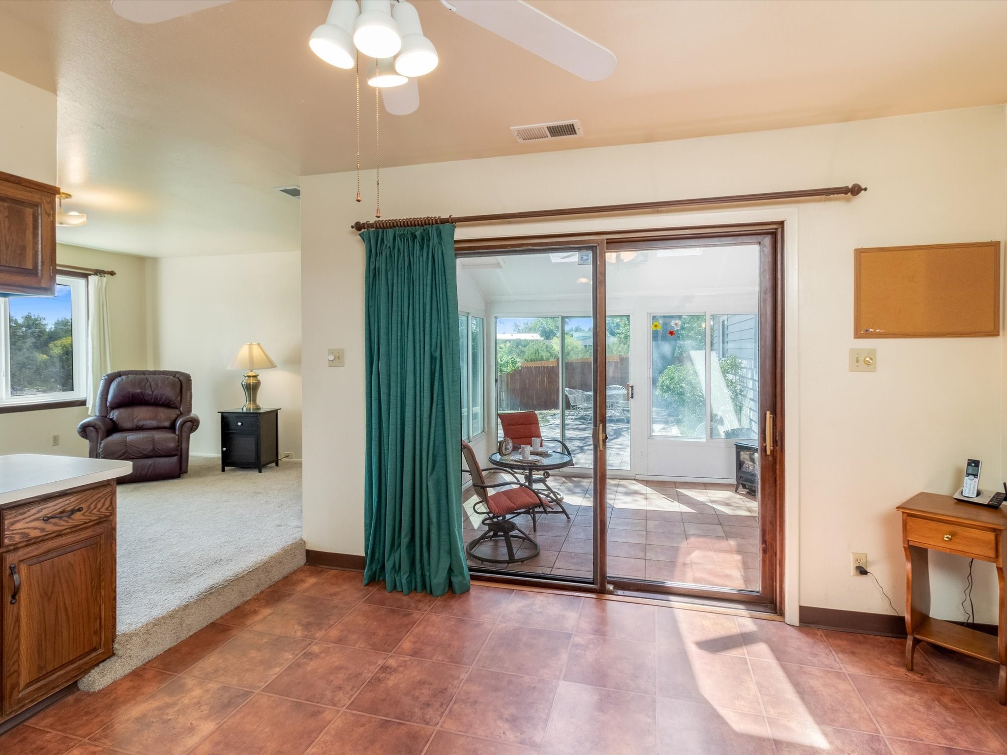 Tiled room with sliding glass doors to an enclosed patio and a carpeted sitting area.