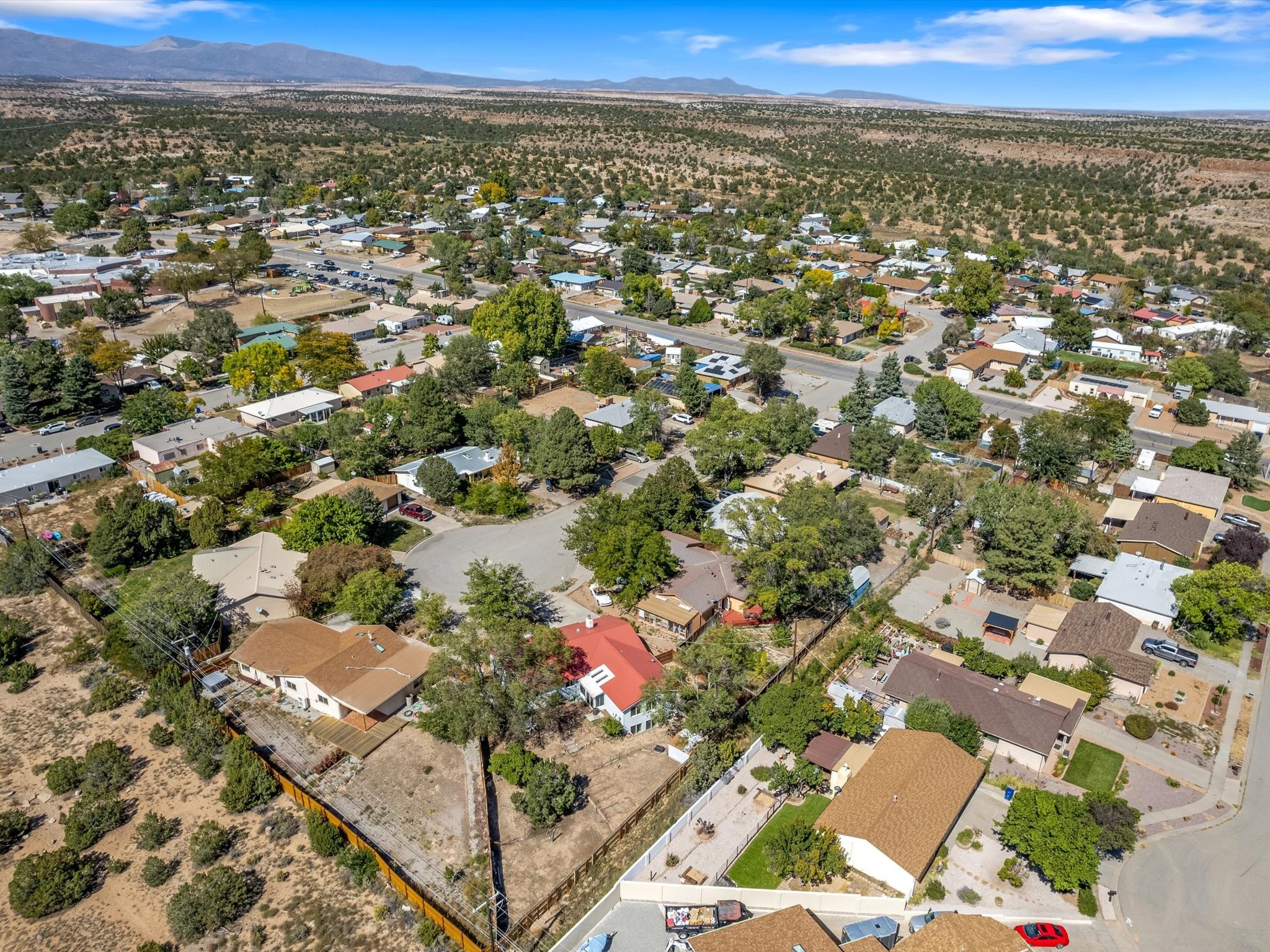 Aerial view of a White Rock neighborhood with homes, dry desert terrain, and distant mountains.