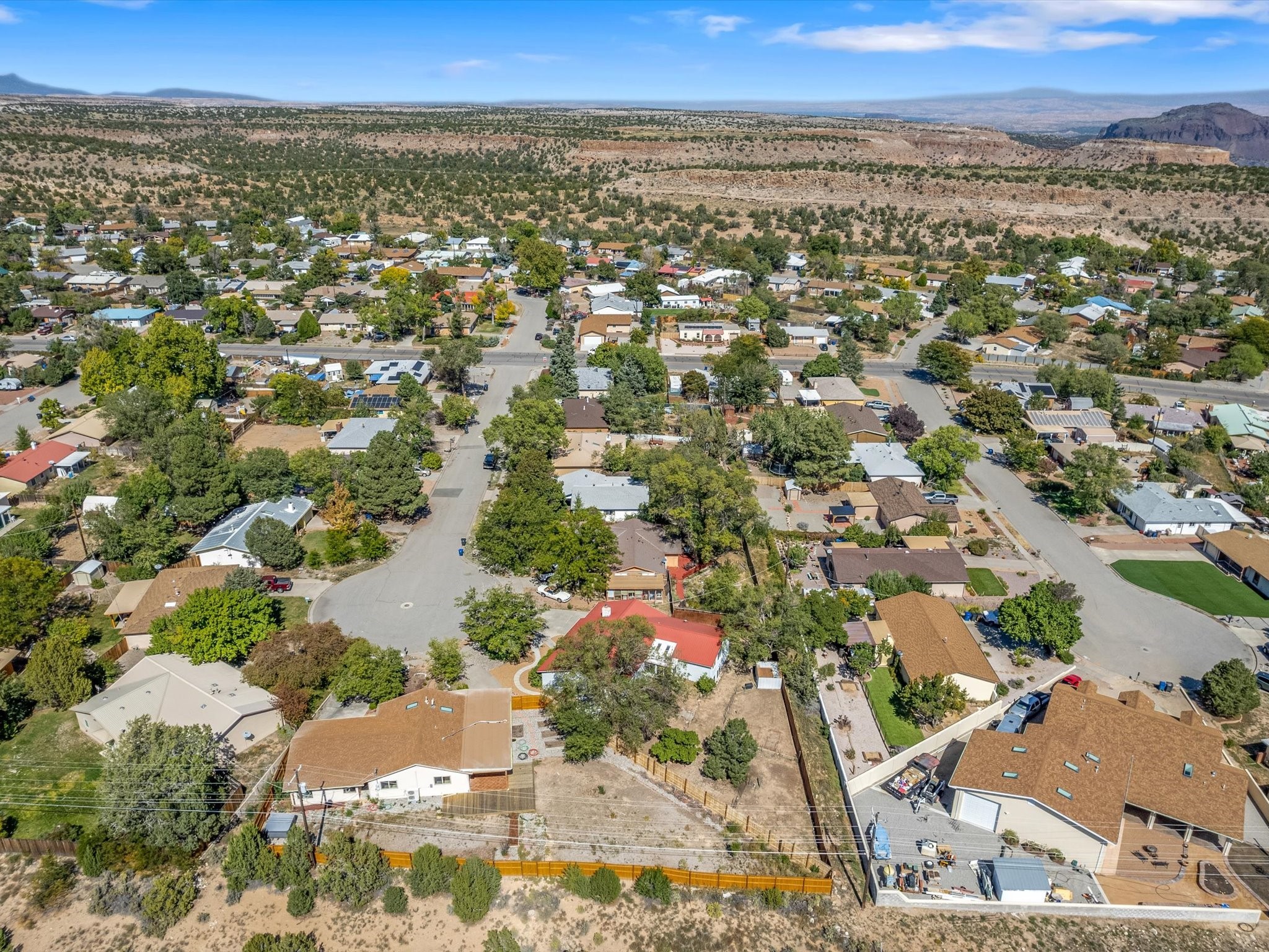 Aerial view of a tree-lined neighborhood with desert mesas and mountains beyond.