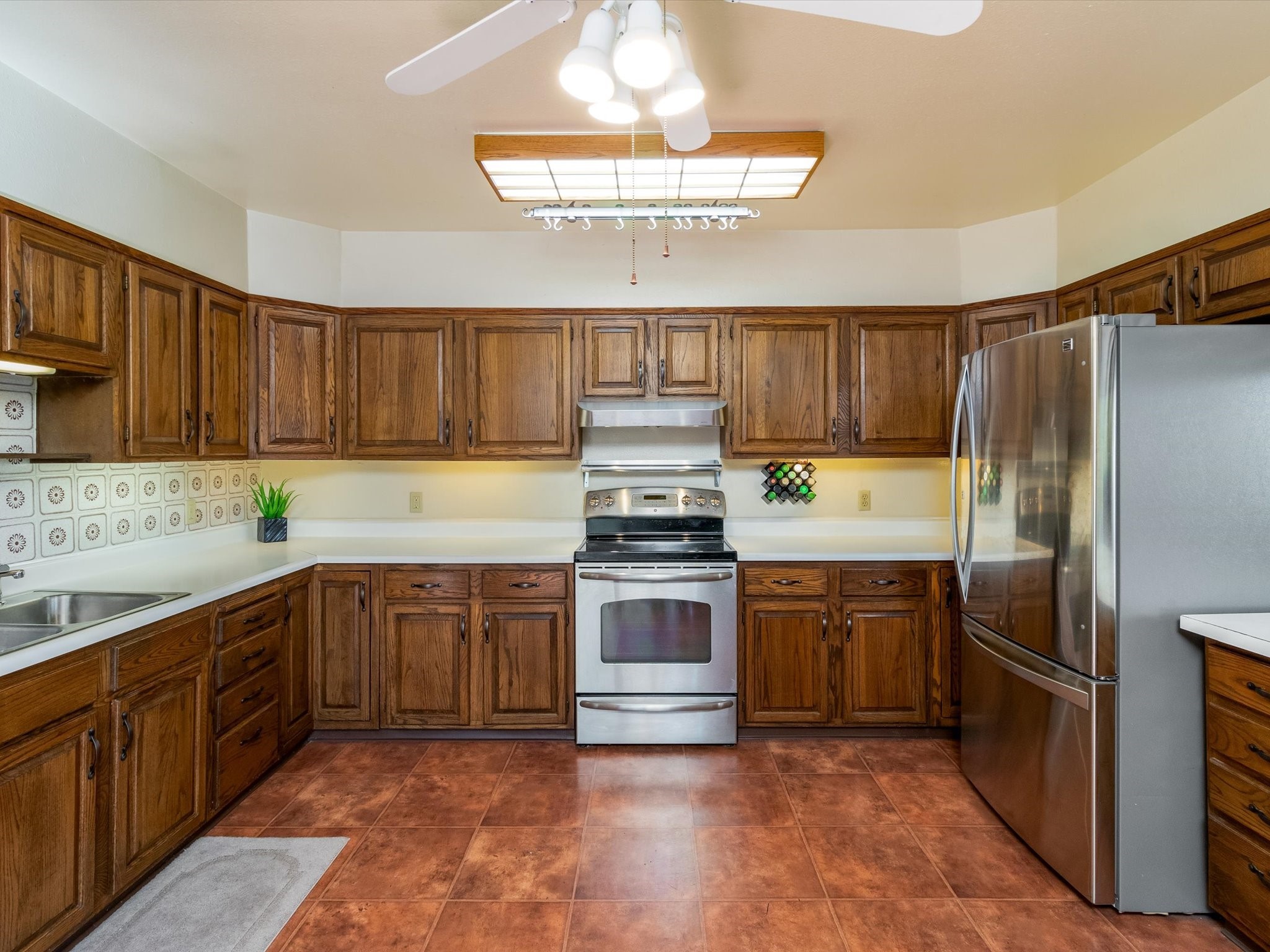 Kitchen with dark wood cabinets, terracotta tile floors, and stainless steel appliances.