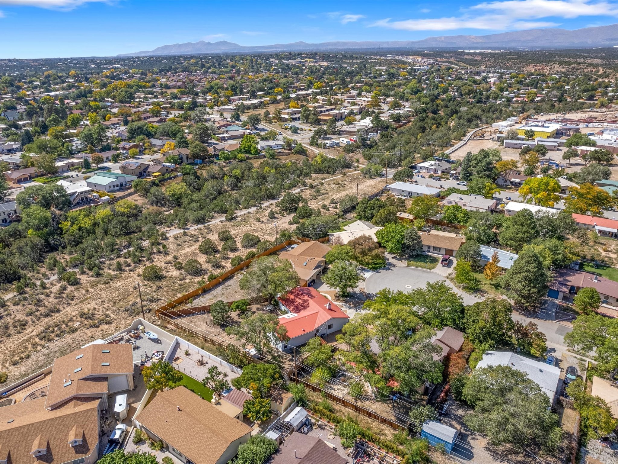 Aerial neighborhood view with a cul-de-sac, open scrubland, and distant mountains.
