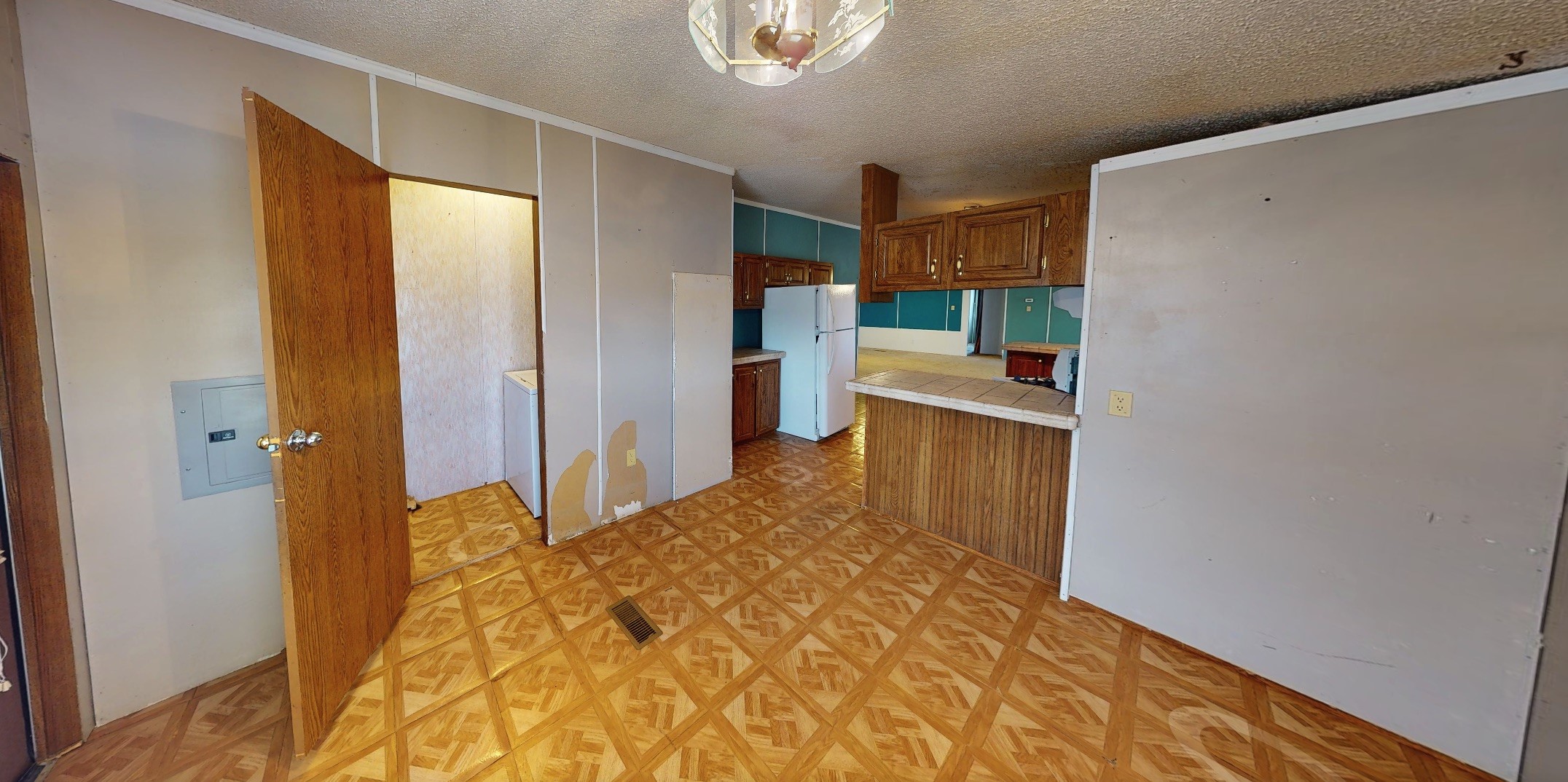 Vacant kitchen and dining area with turquoise walls, wood cabinets, and patterned vinyl flooring.