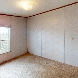 Empty room with patterned walls, dark wood trim, and a small window.