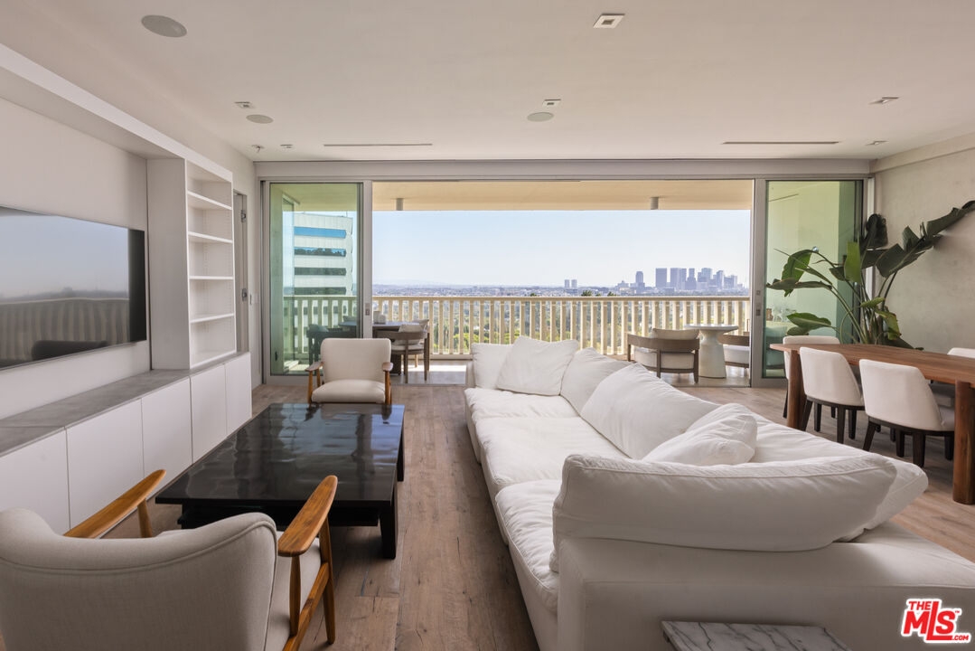 Modern living room with a white sectional and balcony overlooking a distant city skyline.