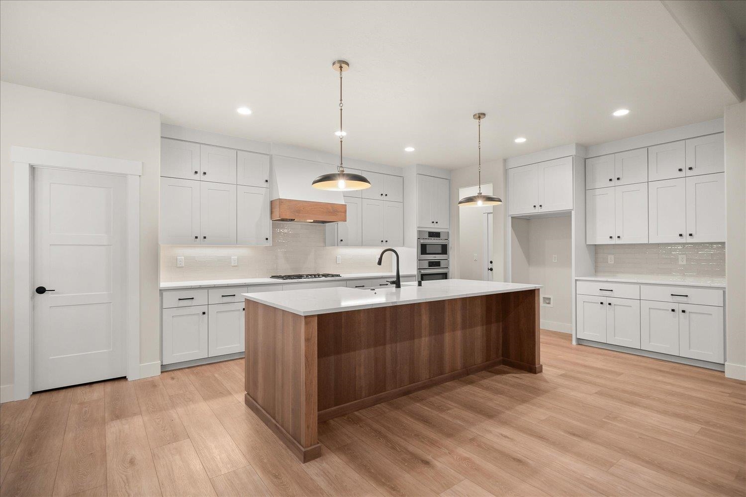 Kitchen with a large walnut-finished island, white cabinetry, and stainless steel double ovens.