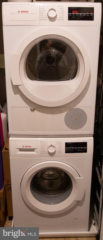 Stacked white Bosch washer and dryer with front-loading doors, digital controls, and a vent grille.