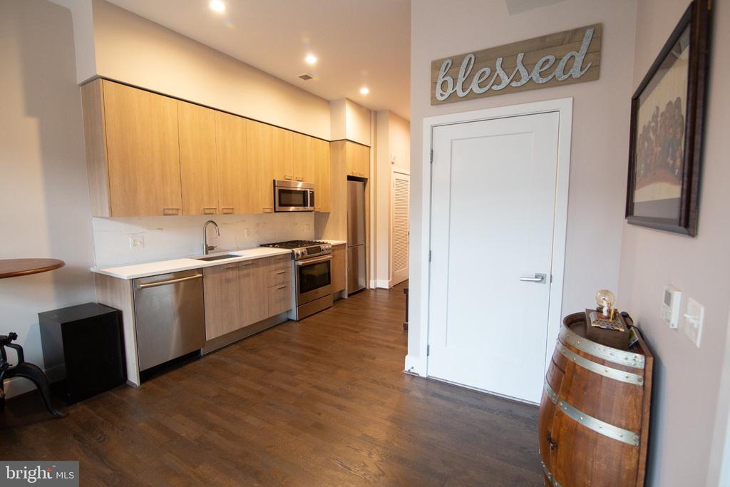 Kitchen with light wood cabinets, stainless steel appliances, and dark hardwood flooring.