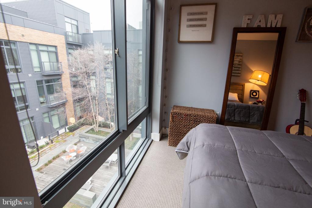 Bedroom with a floor-to-ceiling window overlooking a landscaped courtyard.