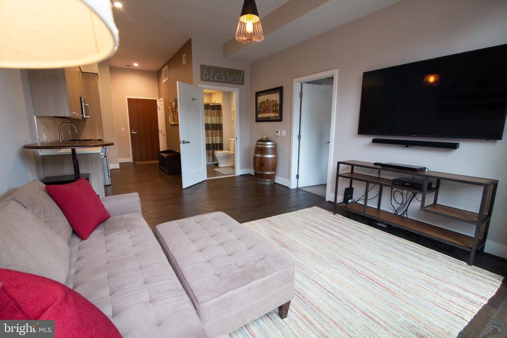 Furnished living room with a gray sectional, striped rug, and wall-mounted television.