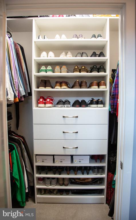 Built-in closet with shoe shelves, three drawers, and hanging clothes on both sides.