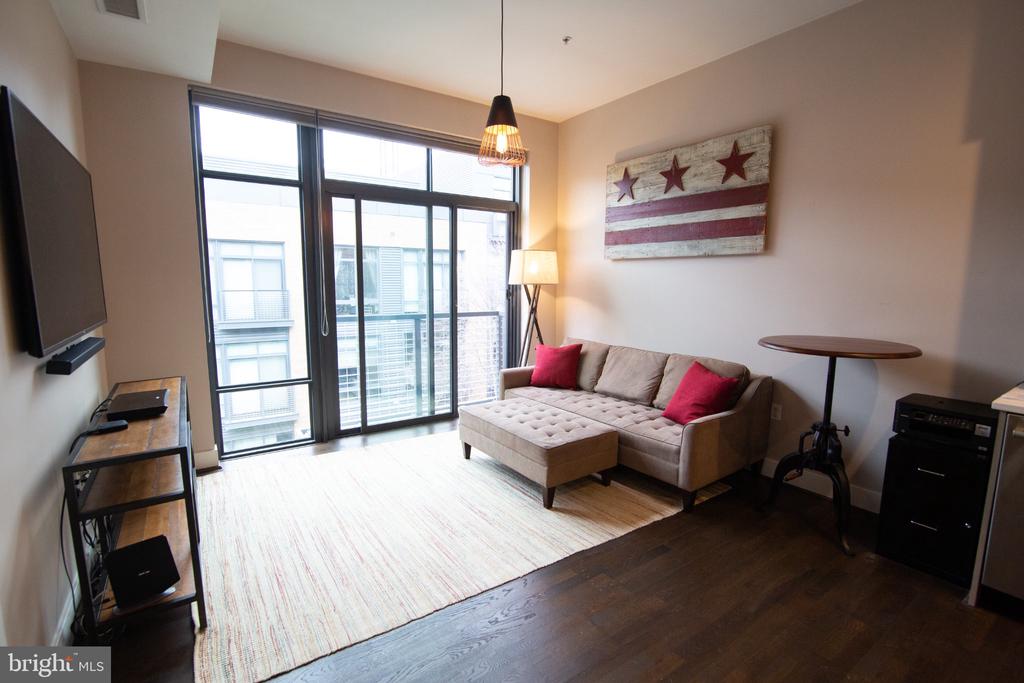 Furnished living room with a beige sectional, red pillows, sliding glass doors, and distressed flag artwork.